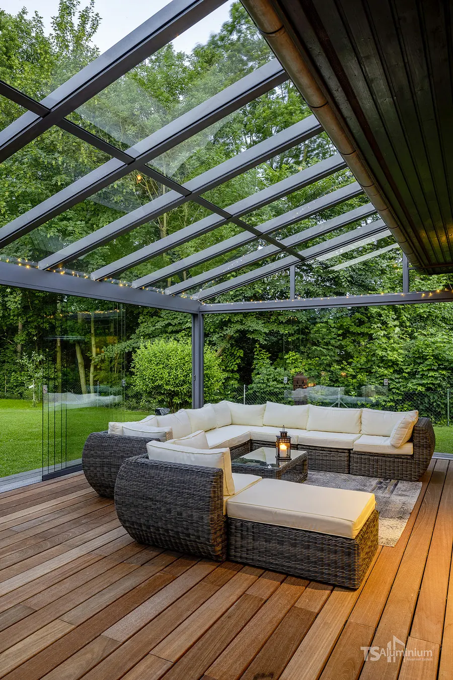 Lounge unter dem Glasdach eines Wintergartens am Abend mit Lichterkette