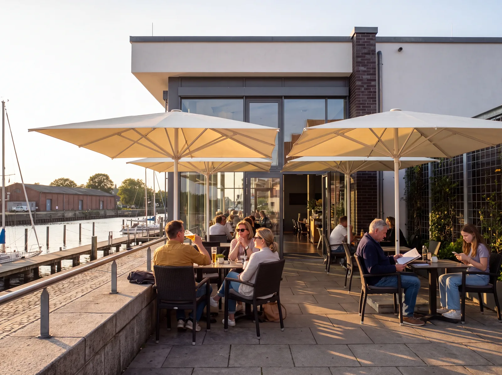 Symbolbild, mit KI erstellt: Cremefarbene Großschirme über einer Restaurantterrasse am Hafen, Gäste an Tischen darunter