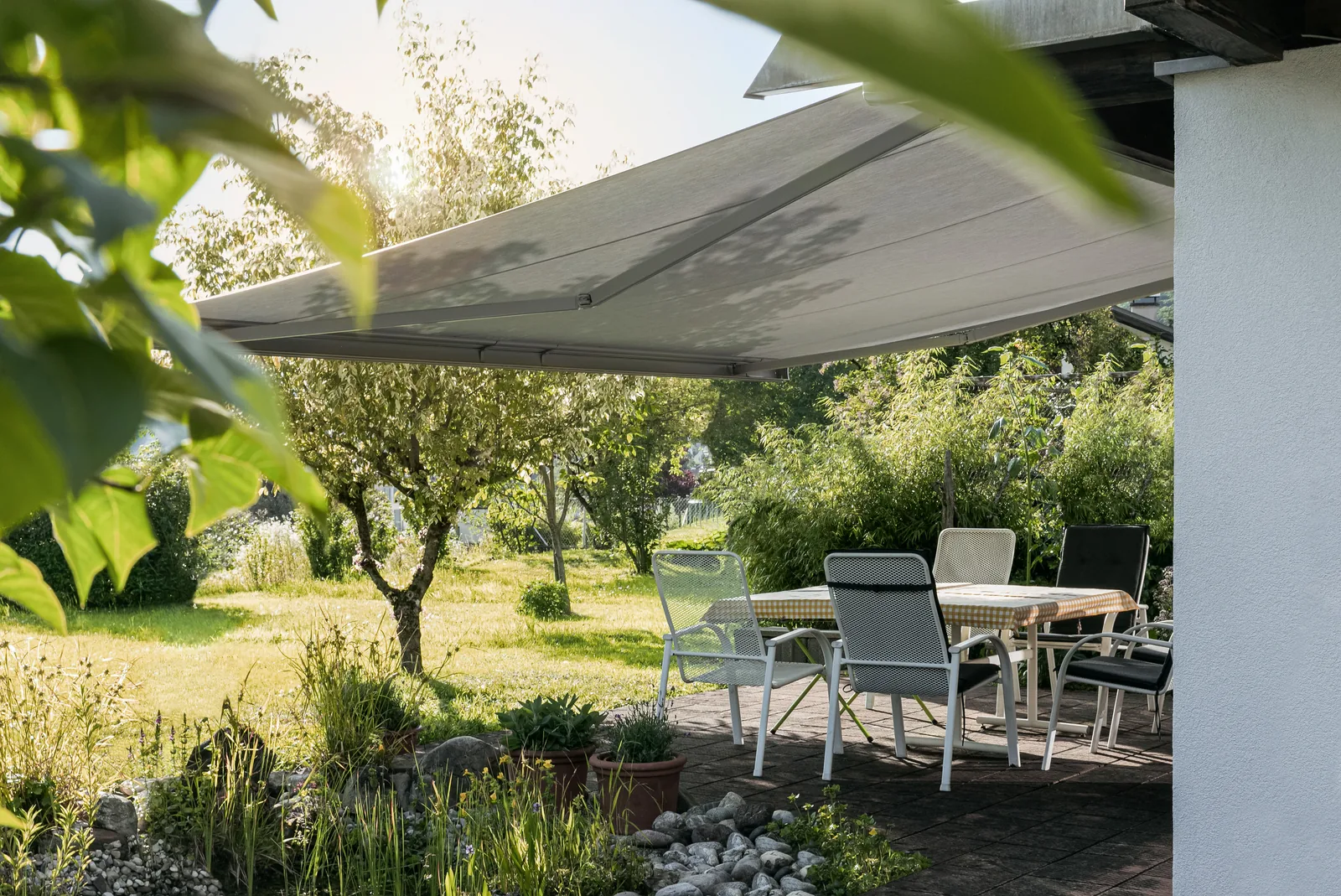 Ausgefahrene Gelenkarmmarkise über einer Gartenterrasse